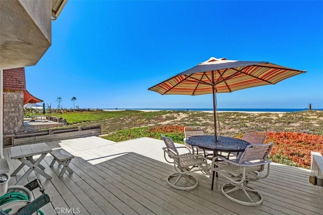 deck with outdoor dining area and a water view