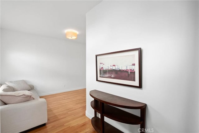 sitting room featuring baseboards and light wood-type flooring