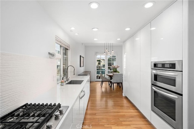 kitchen with modern cabinets, a sink, stainless steel appliances, and white cabinets