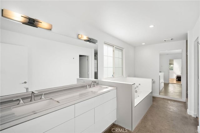 full bathroom with double vanity, concrete floors, a sink, and a garden tub