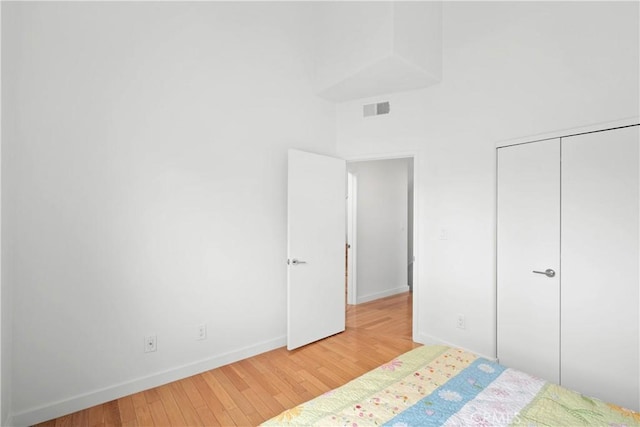 bedroom featuring baseboards, visible vents, a closet, and wood finished floors