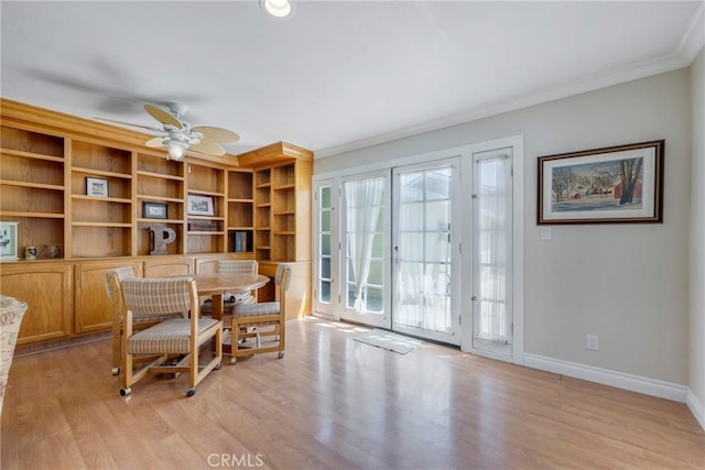 dining area featuring light wood-type flooring, a ceiling fan, baseboards, and ornamental molding