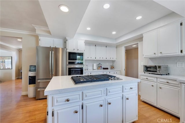 kitchen with white cabinets, stainless steel appliances, light countertops, and a kitchen island