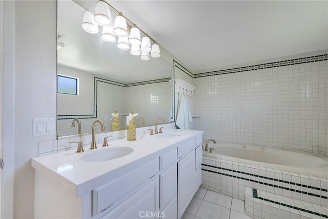 bathroom with tiled tub, tile patterned flooring, a sink, and tile walls