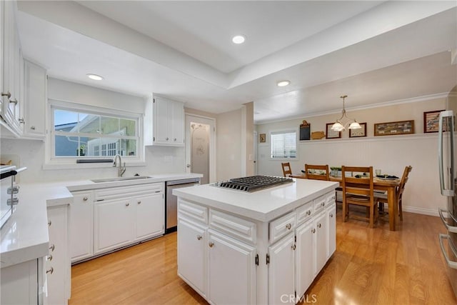 kitchen with white cabinetry, light wood finished floors, stainless steel appliances, and a sink
