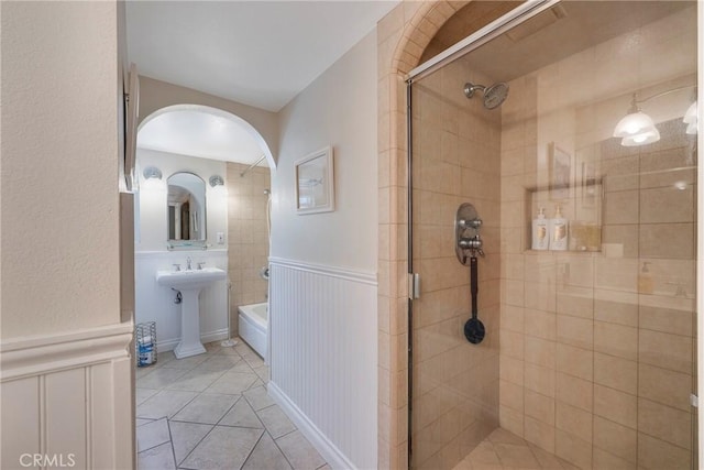 full bathroom with a shower stall, tile patterned flooring, a sink, and wainscoting