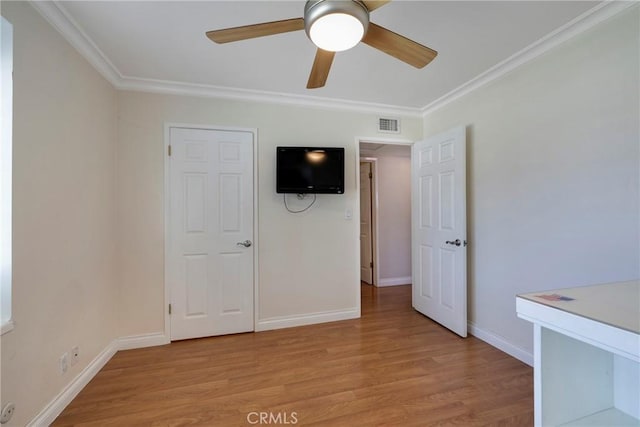 unfurnished bedroom with baseboards, crown molding, and light wood-style floors