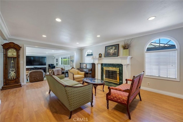 living room with recessed lighting, crown molding, baseboards, a fireplace, and light wood-style flooring