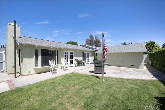 back of property with a chimney, french doors, a yard, a patio, and stucco siding