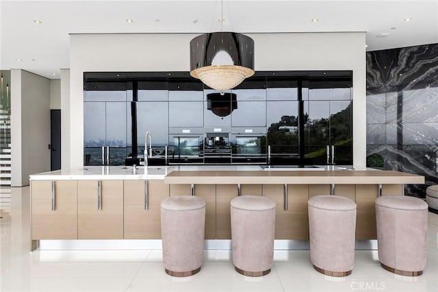 kitchen featuring a breakfast bar area, decorative light fixtures, oven, a sink, and modern cabinets