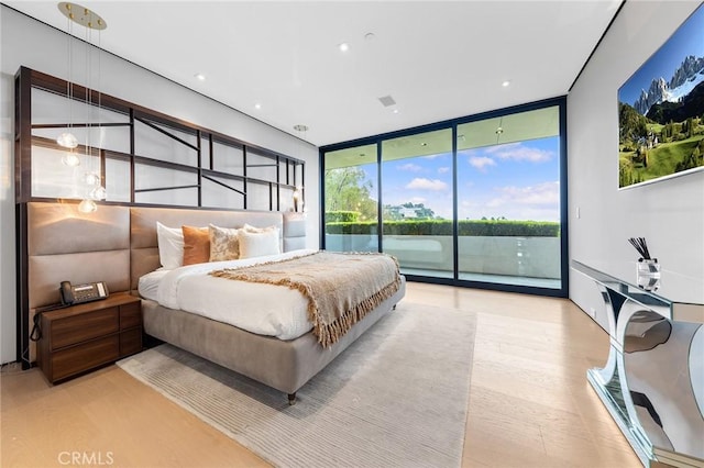 bedroom with wood finished floors, recessed lighting, access to outside, and a wall of windows