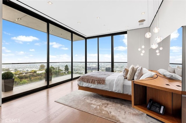 unfurnished bedroom with wood finished floors and a wall of windows
