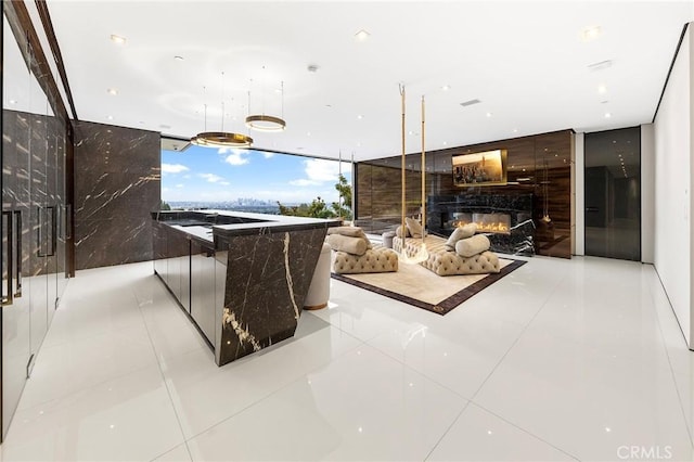 interior space featuring visible vents, floor to ceiling windows, tile patterned flooring, and a glass covered fireplace