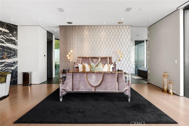 bedroom featuring wallpapered walls, wood finished floors, recessed lighting, and an accent wall