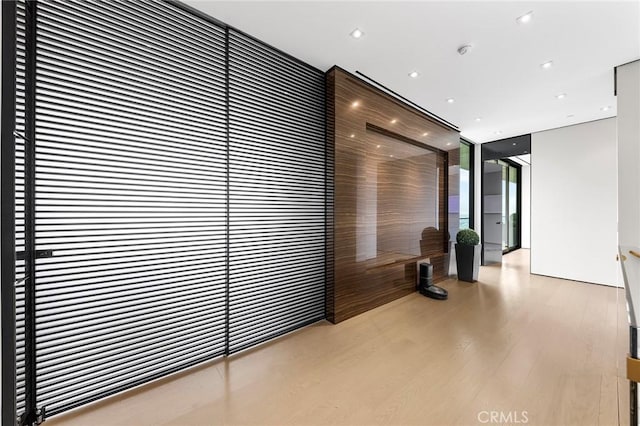 hall featuring recessed lighting, a wall of windows, and wood finished floors