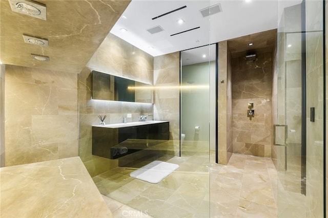 bathroom with toilet, vanity, a stall shower, and tile walls