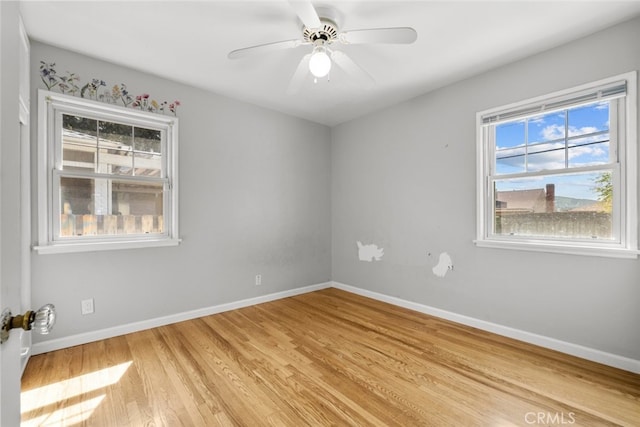 spare room with baseboards, light wood-type flooring, and ceiling fan