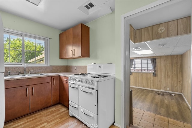 kitchen with light countertops, a sink, light wood-style floors, range with two ovens, and a paneled ceiling