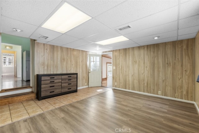 interior space with visible vents, wood finished floors, wood walls, and a paneled ceiling