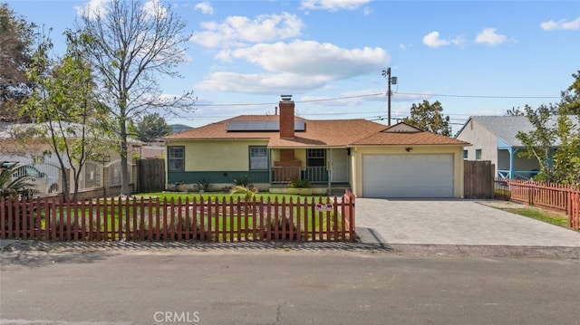 ranch-style home featuring solar panels, a fenced front yard, an attached garage, and driveway