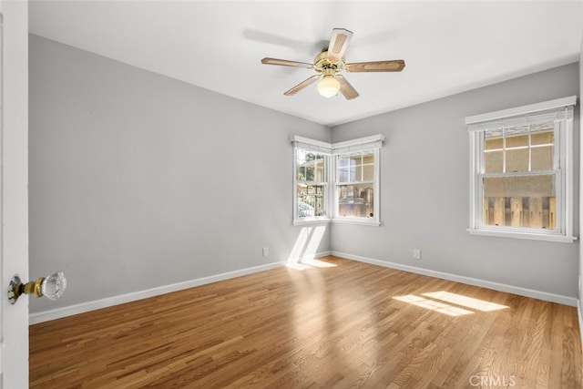 unfurnished room with a ceiling fan, baseboards, and wood finished floors