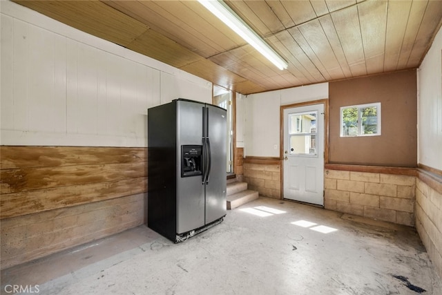 kitchen with concrete floors, black refrigerator with ice dispenser, and wood ceiling