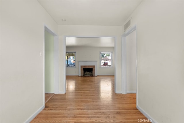 corridor featuring baseboards, light wood-style flooring, and visible vents