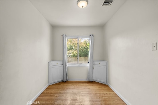 empty room with baseboards, visible vents, and light wood-type flooring