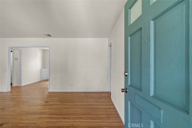 foyer entrance with baseboards, light wood finished floors, and visible vents
