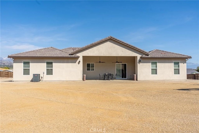 rear view of house with stucco siding, a tile roof, and ceiling fan