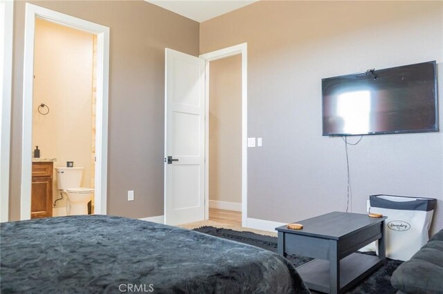 bedroom with ensuite bath and baseboards