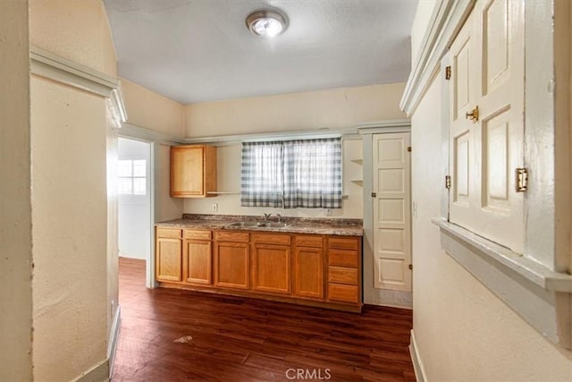 3417 4th Ave, Los Angeles, CA 90018 - kitchen with baseboards, dark wood-style flooring, a sink, a textured wall, and brown cabinets