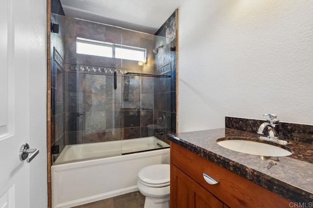 bathroom with vanity, shower / bath combination with glass door, and toilet