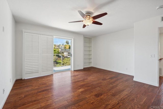 unfurnished room featuring a ceiling fan, baseboards, built in shelves, and wood finished floors