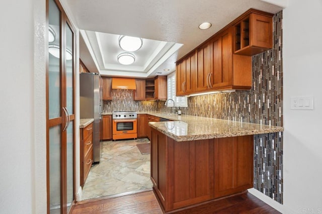 kitchen with open shelves, a peninsula, ventilation hood, brown cabinets, and appliances with stainless steel finishes