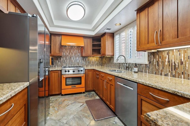 kitchen featuring stainless steel appliances, brown cabinetry, a sink, and wall chimney exhaust hood