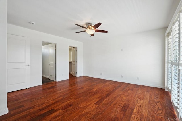 unfurnished bedroom with baseboards, ceiling fan, wood finished floors, and a spacious closet