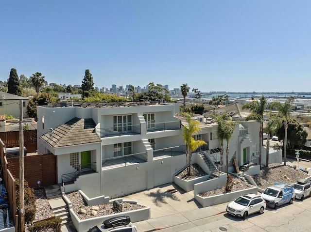 exterior space featuring stairway, fence, a balcony, and stucco siding