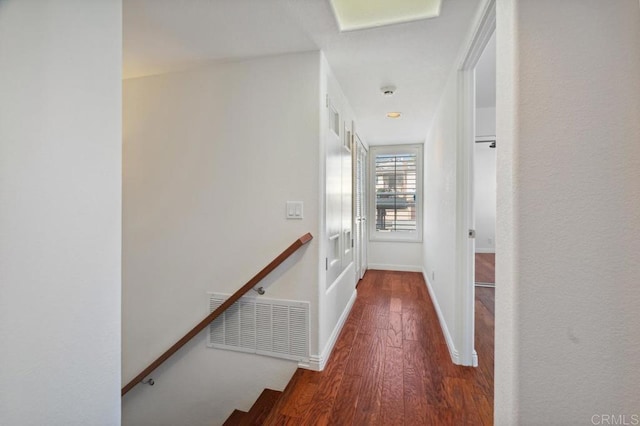 corridor with visible vents, baseboards, wood finished floors, and an upstairs landing