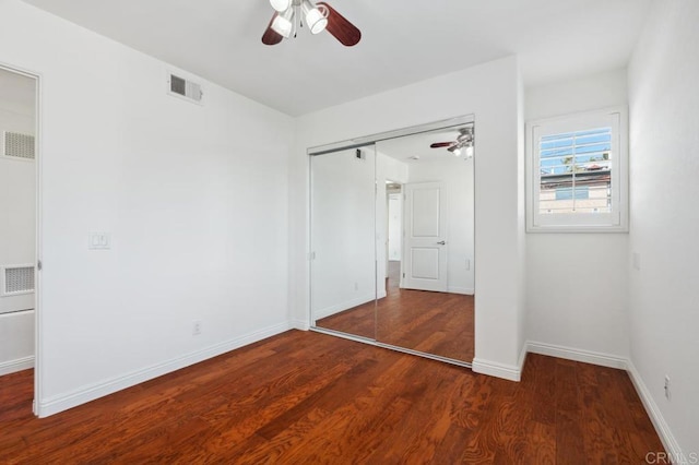 unfurnished bedroom with a closet, wood finished floors, and visible vents