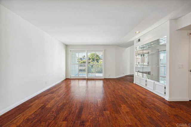 spare room featuring baseboards and wood finished floors
