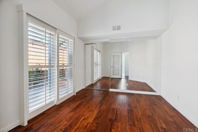 empty room with baseboards, visible vents, plenty of natural light, and hardwood / wood-style floors