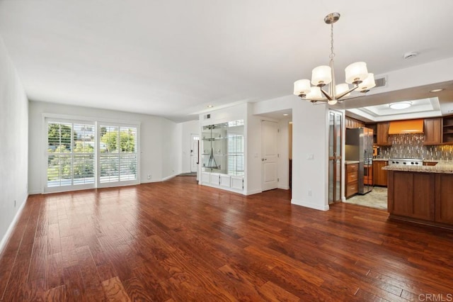 unfurnished living room with baseboards, dark wood-style flooring, a chandelier, and visible vents