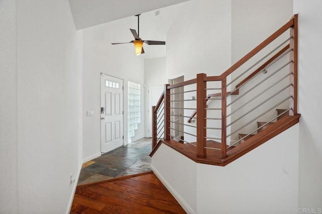 entrance foyer featuring high vaulted ceiling, stairs, a ceiling fan, baseboards, and stone tile flooring