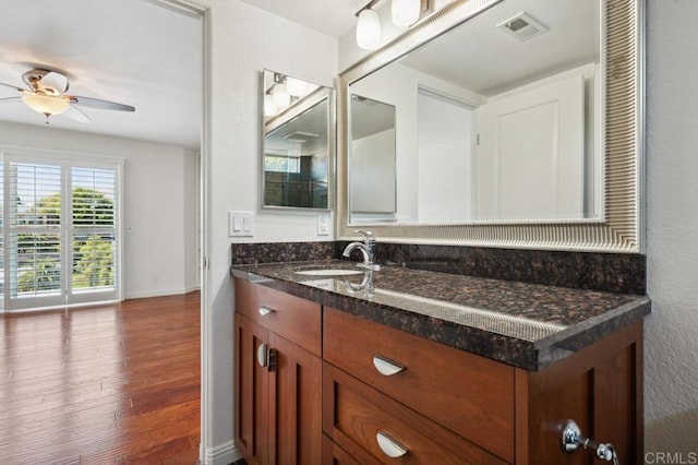 bathroom featuring a ceiling fan, visible vents, wood finished floors, vanity, and baseboards