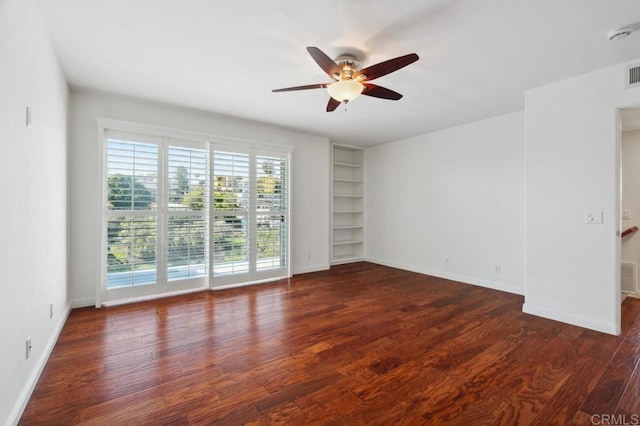 spare room featuring ceiling fan, built in features, baseboards, wood finished floors, and visible vents