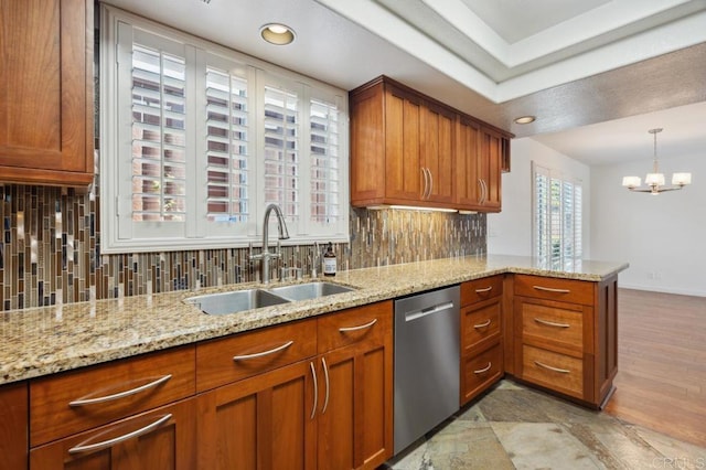 kitchen featuring tasteful backsplash, brown cabinets, dishwasher, a sink, and a peninsula