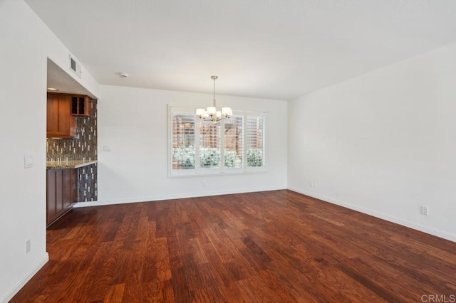 unfurnished dining area featuring an inviting chandelier, baseboards, dark wood-type flooring, and visible vents