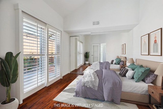 bedroom with high vaulted ceiling, visible vents, multiple windows, and wood finished floors