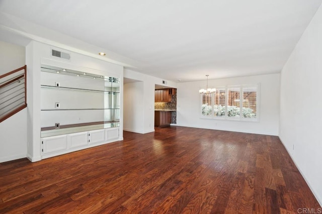 unfurnished living room with baseboards, visible vents, dark wood-style floors, and a notable chandelier